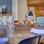 Catered chalet dining table in Morzine with wine, bread and glasses at Chalet La Petite Grange